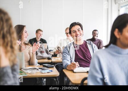 Smiling male and female students in classroom at university Stock Photo