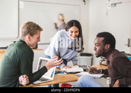 Smiling young man showing smart phone to friends in classroom Stock Photo