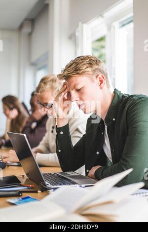 Serious young man using laptop in classroom Stock Photo