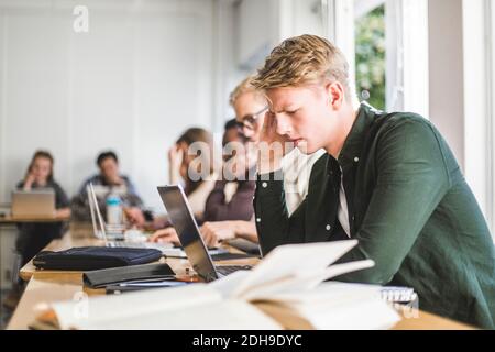 Determined young man using laptop in classroom Stock Photo