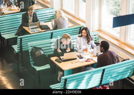 High angle view of male and female students sitting in cafeteria at university Stock Photo
