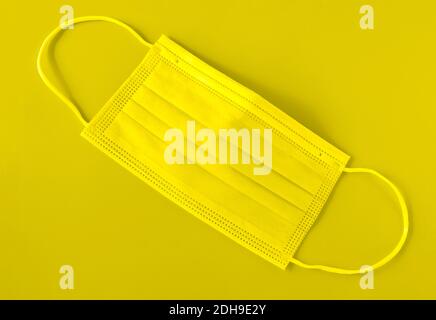 Illuminating yellow panton color 2021 medical mask. Selective, soft focus. Horizontal orientation, top view. Stock Photo