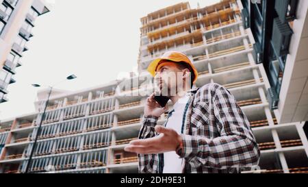 Engineer talking on phone. Architect using phone on construction site. Foreman phone call control process. Construction worker c Stock Photo