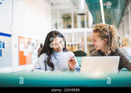 Smiling young female students studying in cafeteria at university Stock Photo