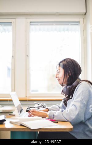 Side view of young female students using laptop in cafeteria at university Stock Photo