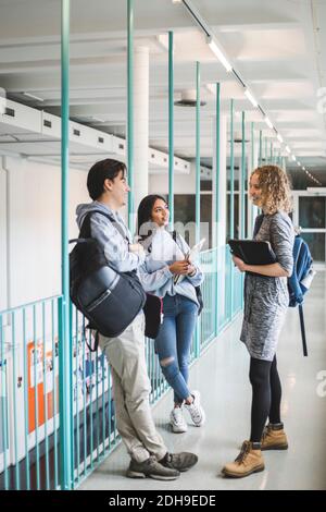 Male and female students talking while standing in corridor of university Stock Photo