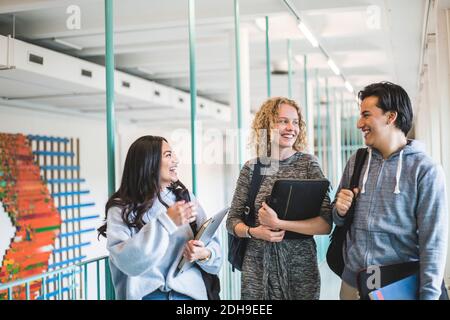 Happy male and female students talking while walking in corridor of university Stock Photo