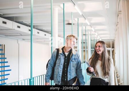 Happy male and female students walking in corridor of university Stock Photo