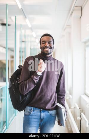Portrait of smiling male student in corridor of university Stock Photo