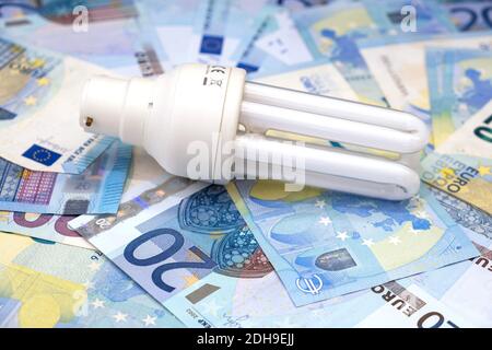 Cost of electricity: compact fluorescent lamp and twenty Euro notes Stock Photo