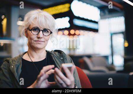 Portrait of confident mature businesswoman using mobile phone in office Stock Photo