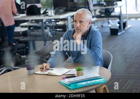 Thoughtful senior businessman taking notes at office Stock Photo