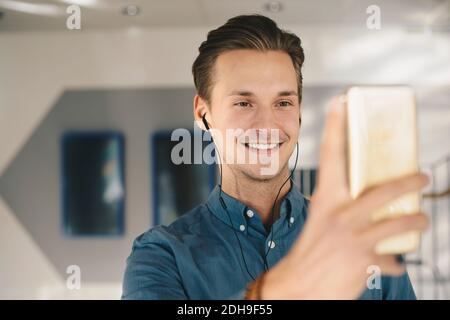 Happy businessman taking selfie through smart phone in office Stock Photo