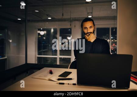 Businessman staring at laptop while thinking in office Stock Photo