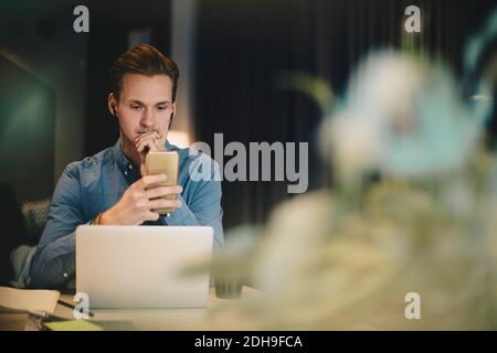 Businessman using smart phone at desk in office Stock Photo