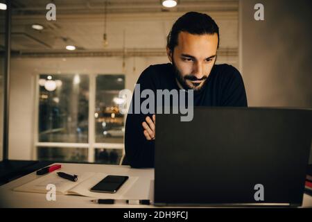 Confident businessman looking at laptop while working late in office Stock Photo