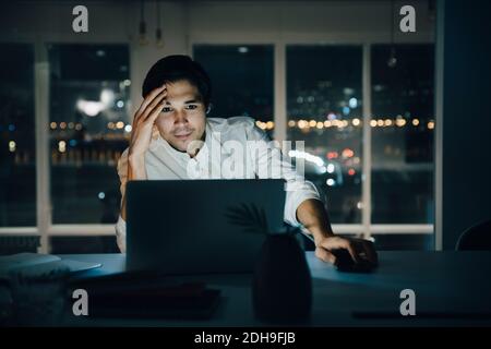 Businessman looking at laptop while working late in dark creative workplace Stock Photo