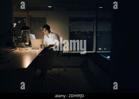 Businessman working late in dark creative office Stock Photo
