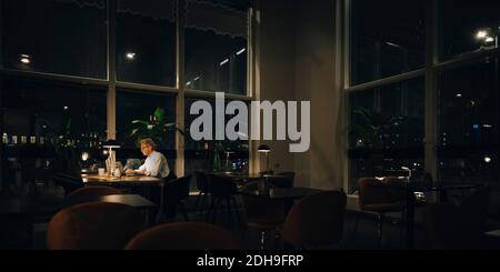 Determined senior businessman working late in dark office at night Stock Photo