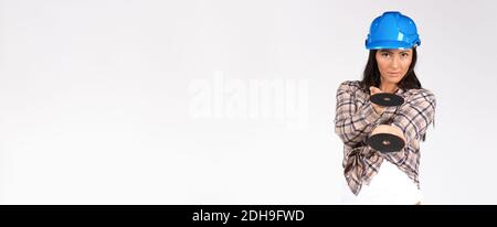 Banner,long format. A woman in a hard hat poses on white background with grinder discs. Construction and gender concept Stock Photo
