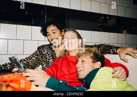 Happy female showing smart phone to friends while sitting in restaurant Stock Photo