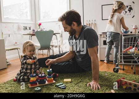 Father and daughters playing with toys in playroom at home Stock Photo