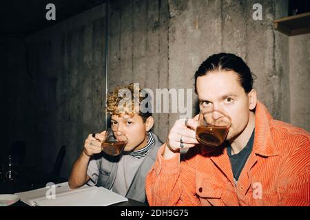 Portrait of smiling entrepreneurs drinking coffee while sitting in creative office Stock Photo