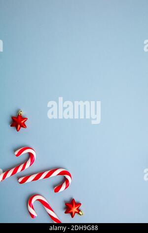 Candy canes and red stars as Christmas decoration over blue background. Stock Photo