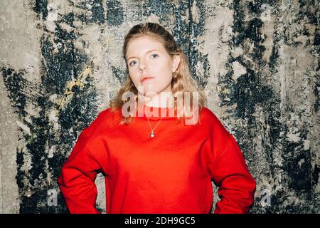 Portrait of female entrepreneur standing against wall at workplace Stock Photo
