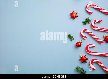 Christmas decorations candy canes and red stars over blue background. Stock Photo