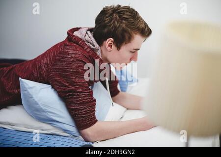 Side view of teenage boy lying on bed at home Stock Photo