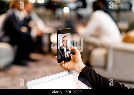 Male and female colleagues talking through video conference on smart phone in office Stock Photo