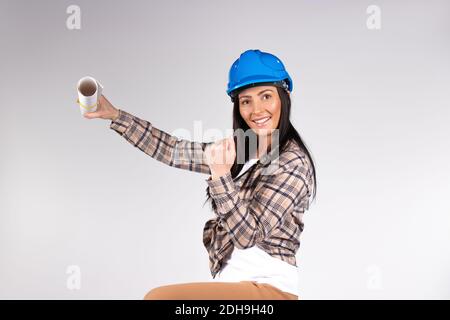Charming happy female architect smiling and holding blueprint, posing on isolated white background. Stock Photo