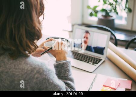 Woman in home office having online meeting with coworker Stock Photo