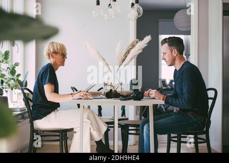 Profile of woman and man at table working from home Stock Photo