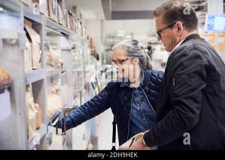 Smiling woman taking food from cabinet while standing with man at supermarket Stock Photo