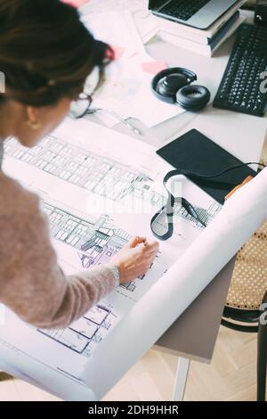 Architect looking at blueprint in office at home Stock Photo