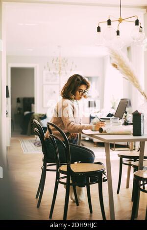 Woman sitting at table working from home Stock Photo