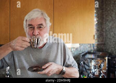 Portrait of senior man drinking coffee while standing in kitchen Stock Photo