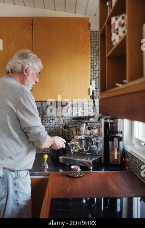 Senior man using coffee maker on kitchen counter at home Stock Photo