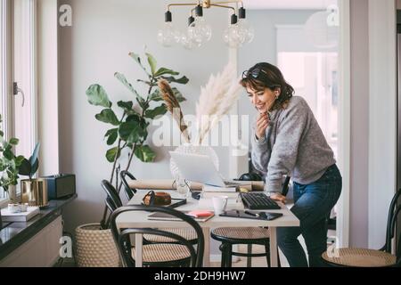 Smiling woman talking on the phone working at home Stock Photo