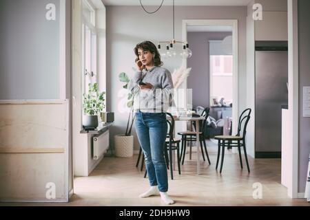 Woman standing at home talking on the phone Stock Photo