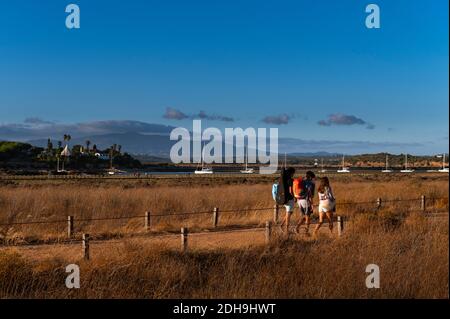 Alvor, Portugal - August 17, 2020: People leaving the beach and walking along the Alvor estuary, near the town of Alvor, in Algarve, Portugal, with th