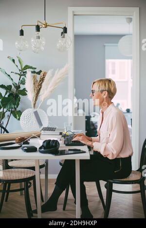 Woman sitting at table working from home Stock Photo