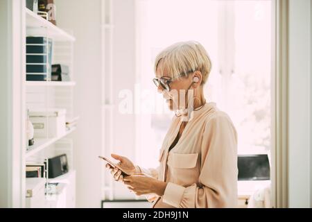 Woman in home office using smartphone Stock Photo