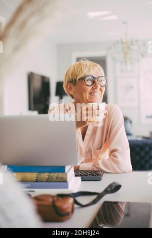 Woman having coffee at table working from home Stock Photo