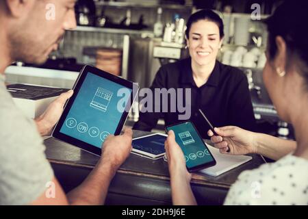 Smiling man using smart phone while women looking in cafe Stock Photo