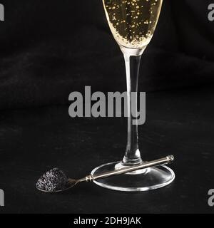 Black caviar and a glass of champagne on a black background with a place for text Stock Photo