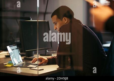 Businessman working on laptop at desk in office during night Stock Photo