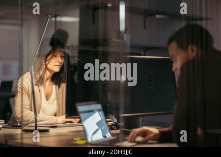 Business colleagues using technology while working late at office Stock Photo